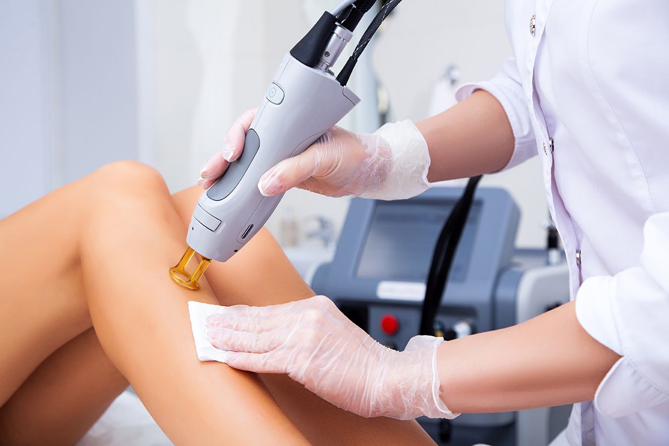 Close-up illustrative photograph of a laser handpiece treating the leg